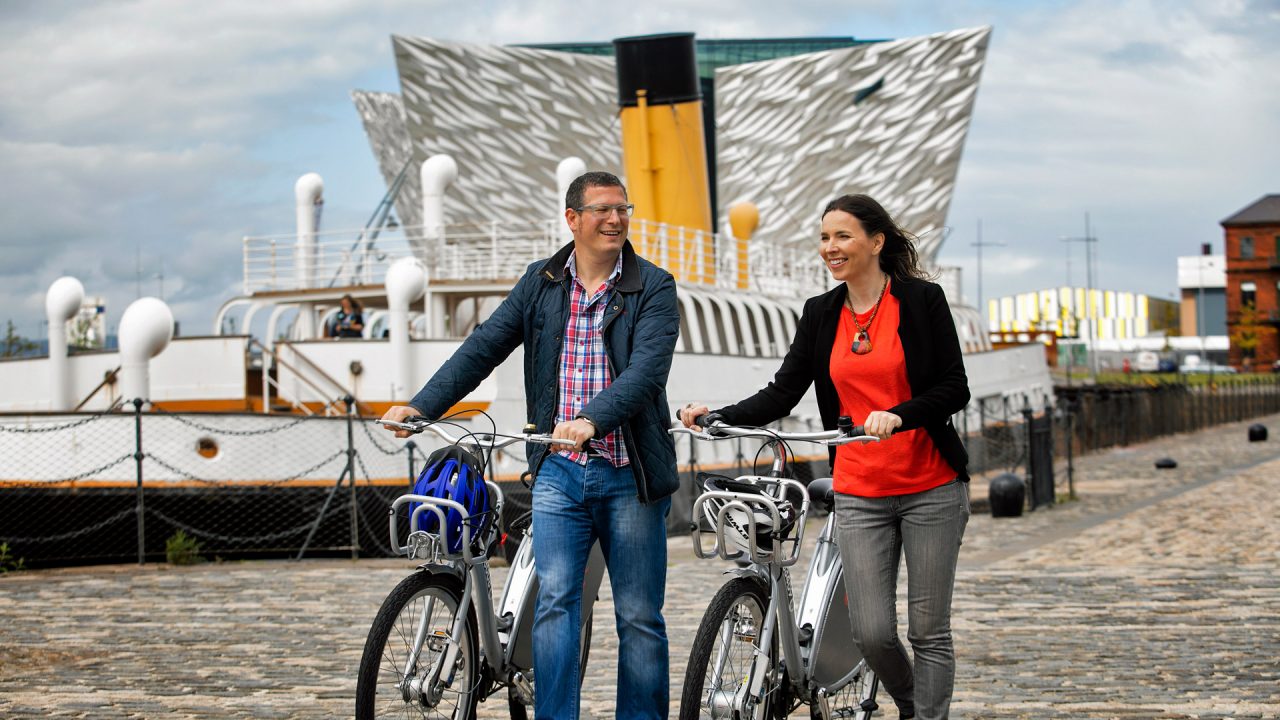 Annual Guide Cover Image 2018 Couple walk bicycles by SS Nomadic in Titanic Quarter