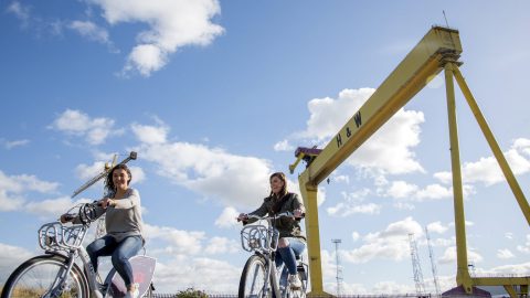 Friends ride Belfast Bikes near Harland and Wolff Cranes